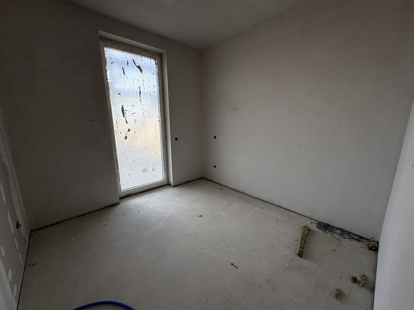 Photo de chantier : même chambre, murs bruts, sol en chape.